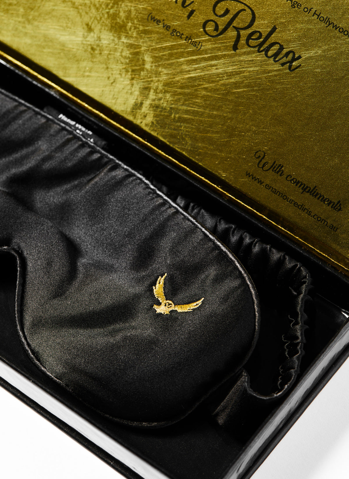 Close up of a silk black eye mask for video production crew in a gold box. Designed by Enamoured Iris