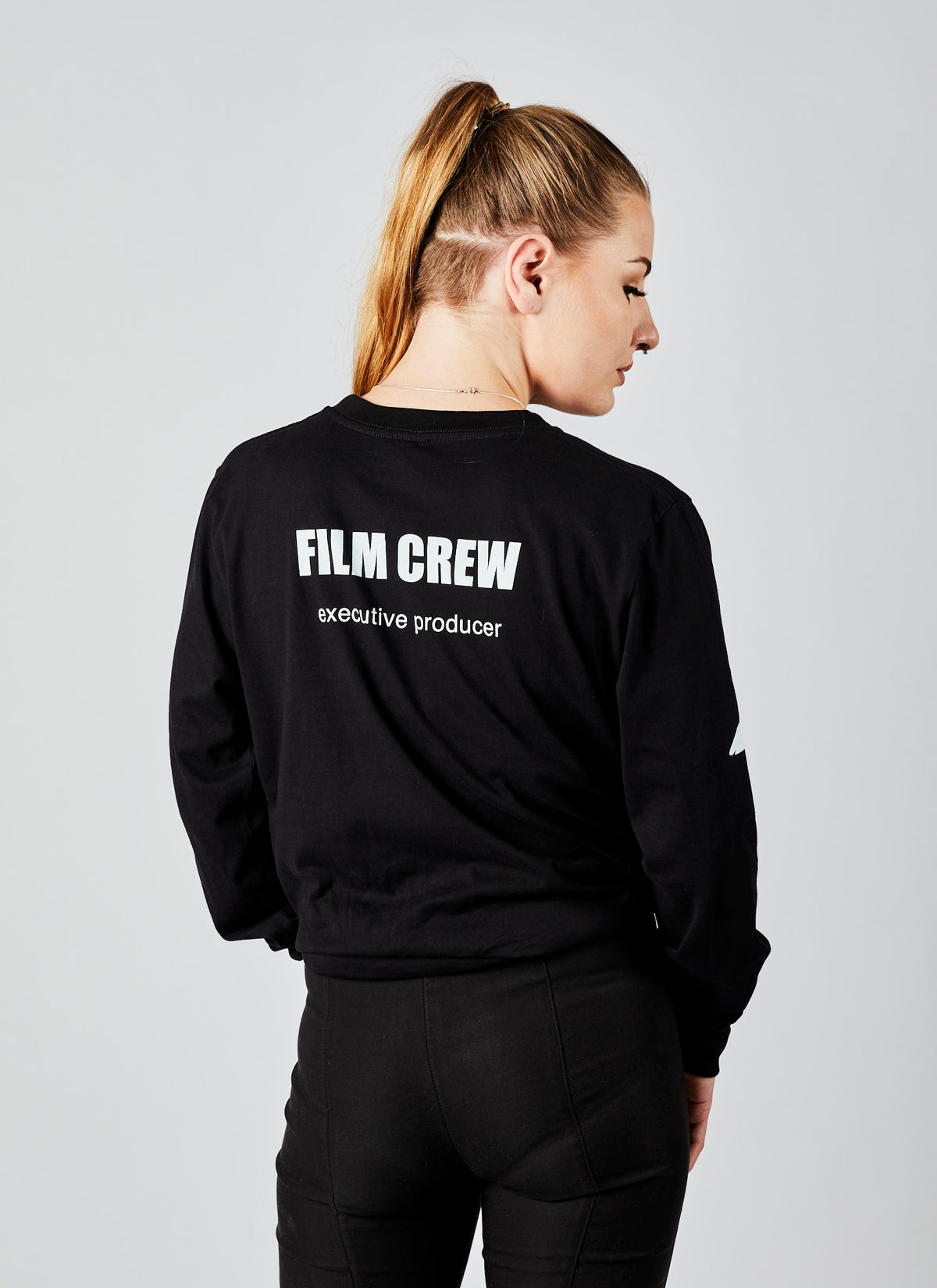 Back of a woman wearing a black, long-sleeved &quot;Executive Producer&quot; film crew shirt from Melbourne video production company, Enamoured Iris.